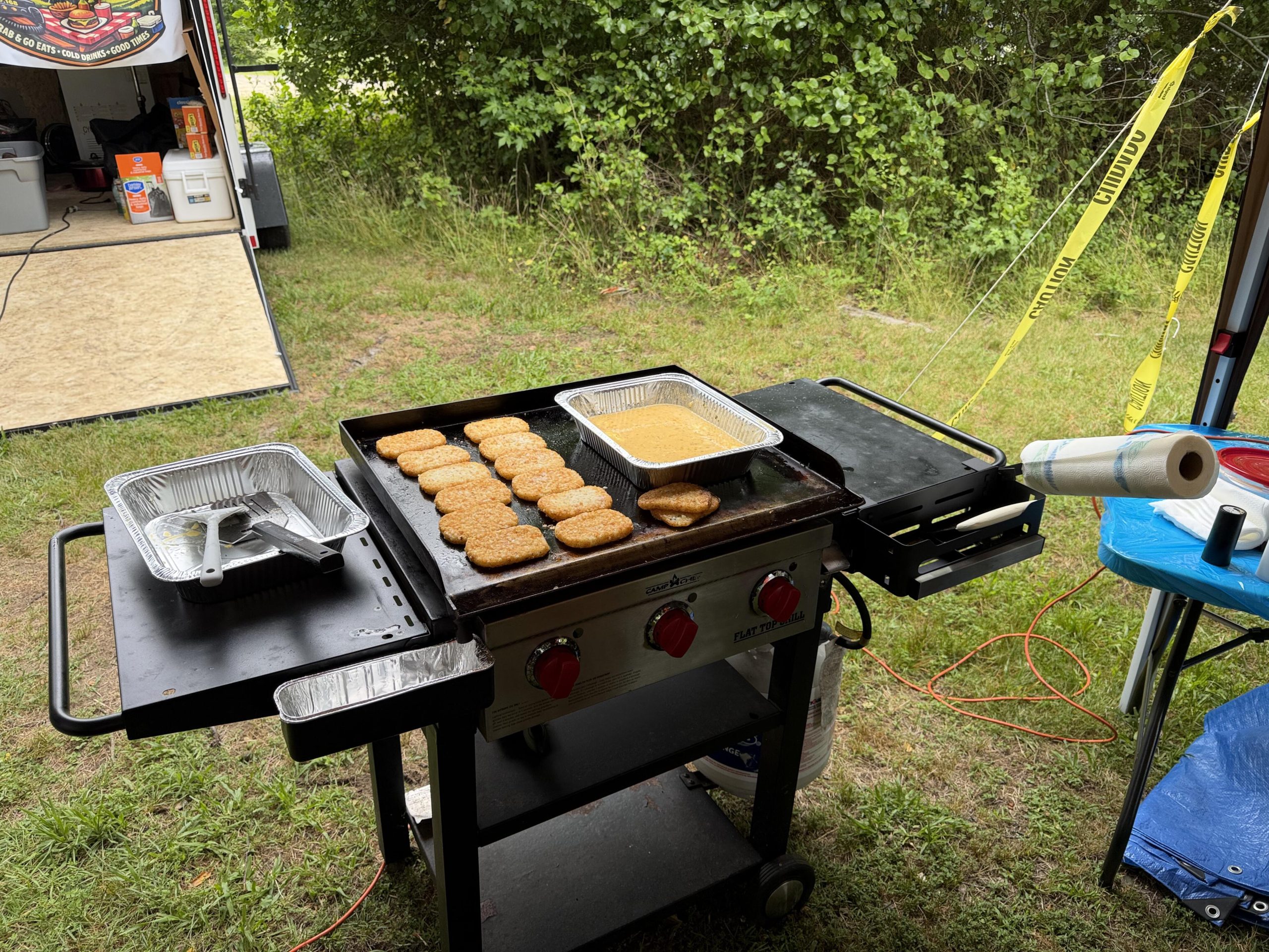 Blackstone flat-top griddle cooking hash brown patties and scrambled eggs in a disposable pan