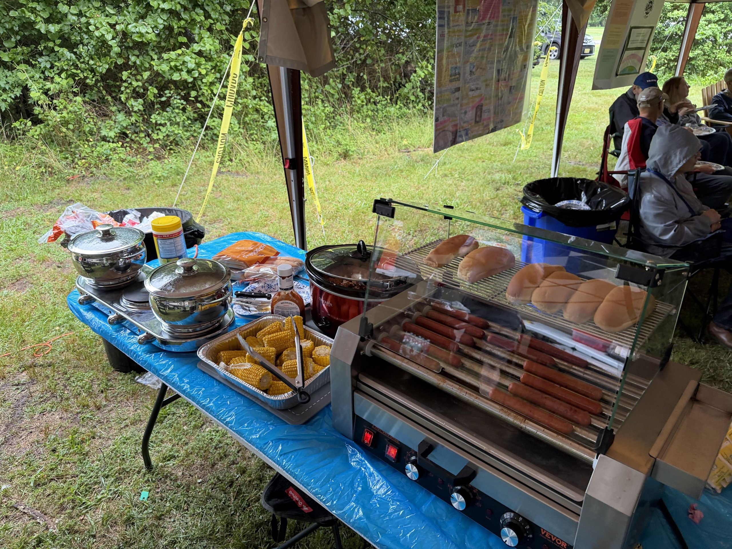 Full Saturday lunch service line with hot plate, crockpot pulled pork, corn on the cob, and hot dog roller with Hebrew National franks