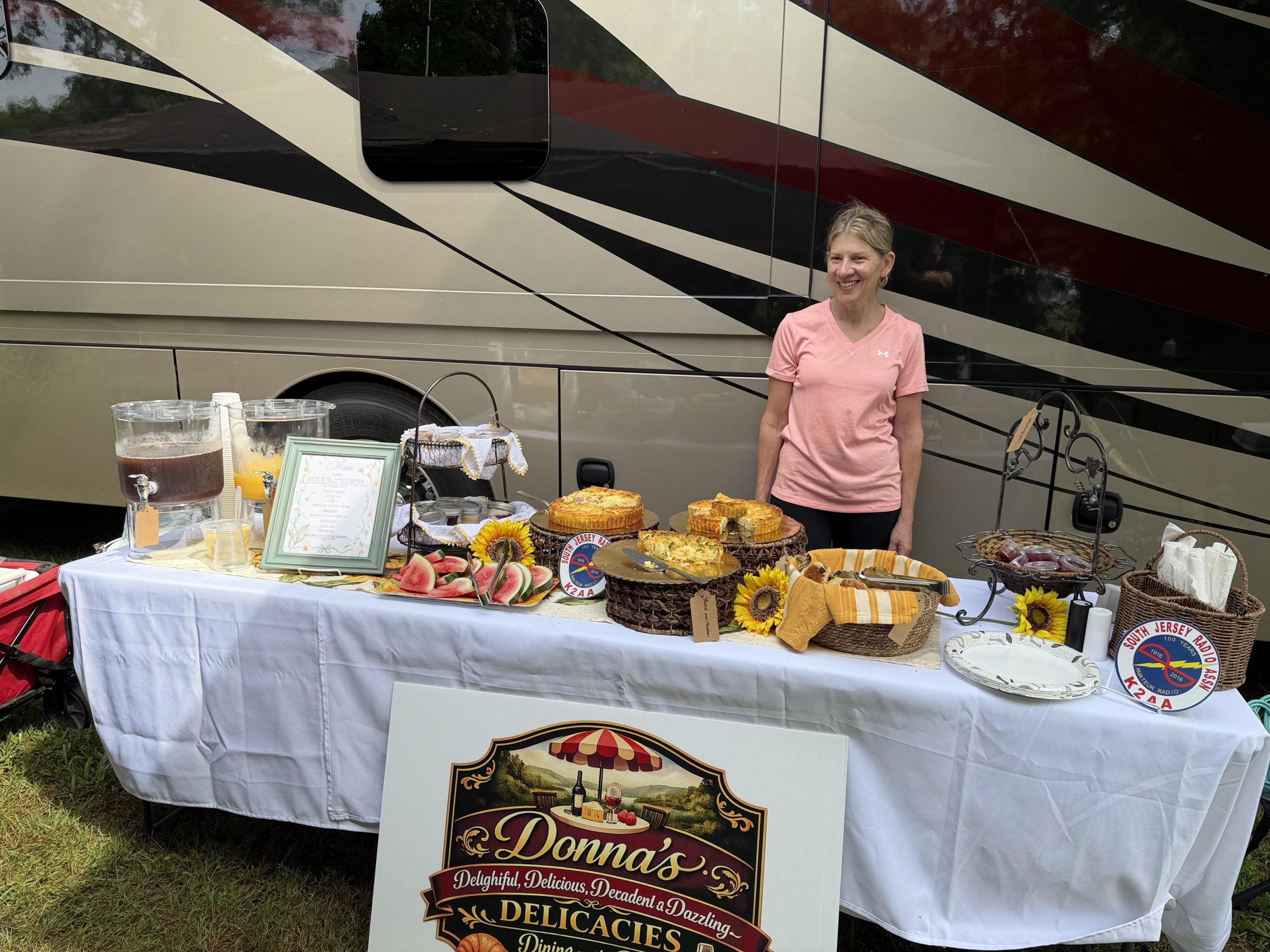 Donna Dantis at the Donna's Delicacies Sunday breakfast table with homemade quiche, parfaits, and the RV commissary behind her