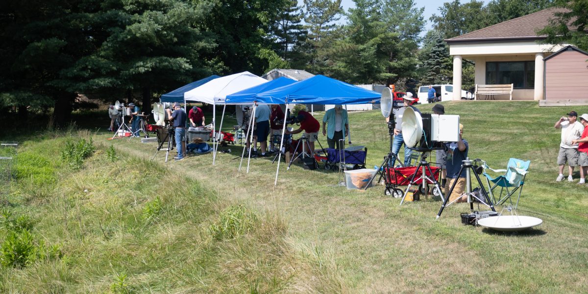 Line of MDS competition stations under canopies along a grassy hillside