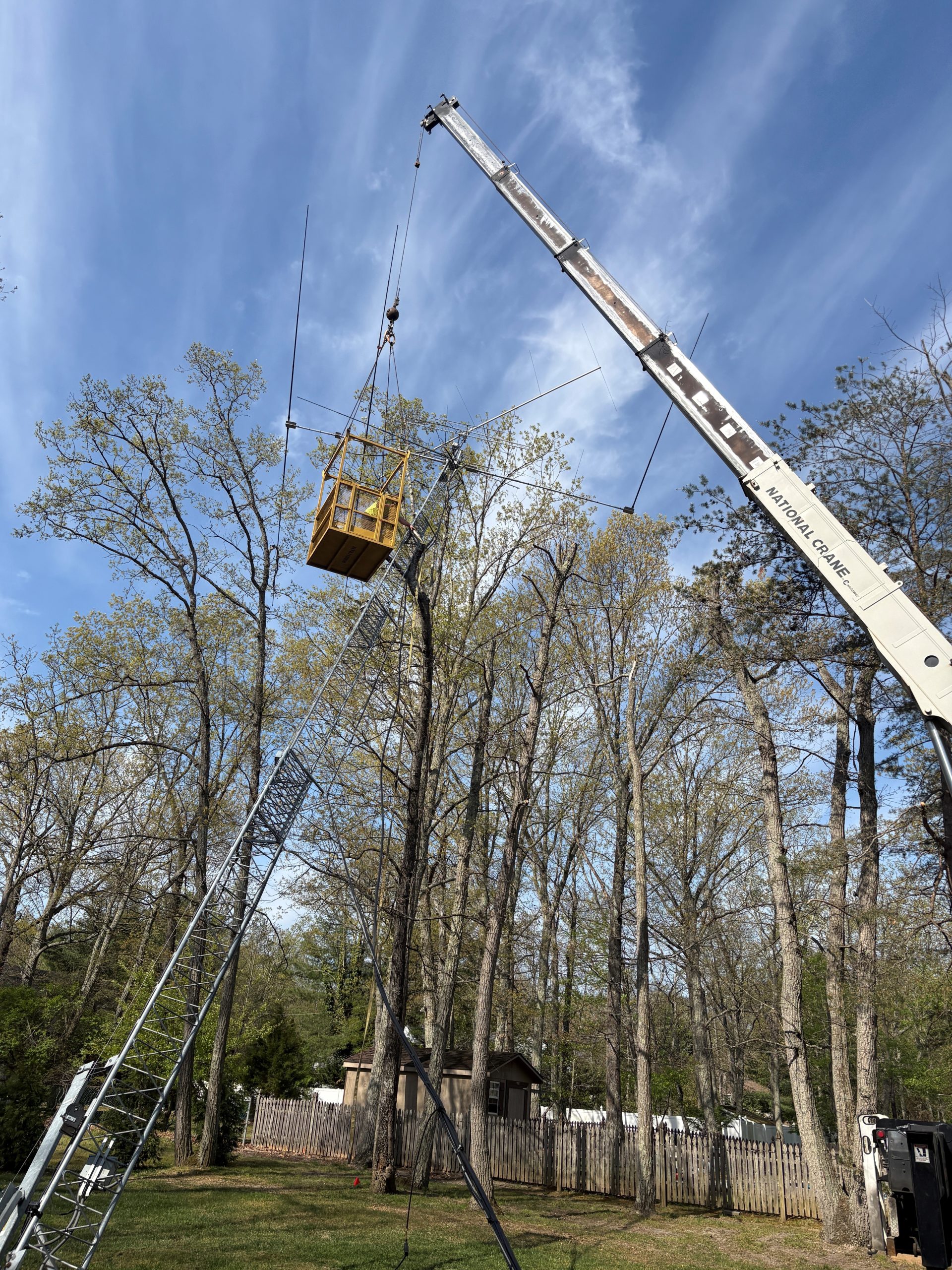 Man basket working the rigging above the treeline as the tower comes free